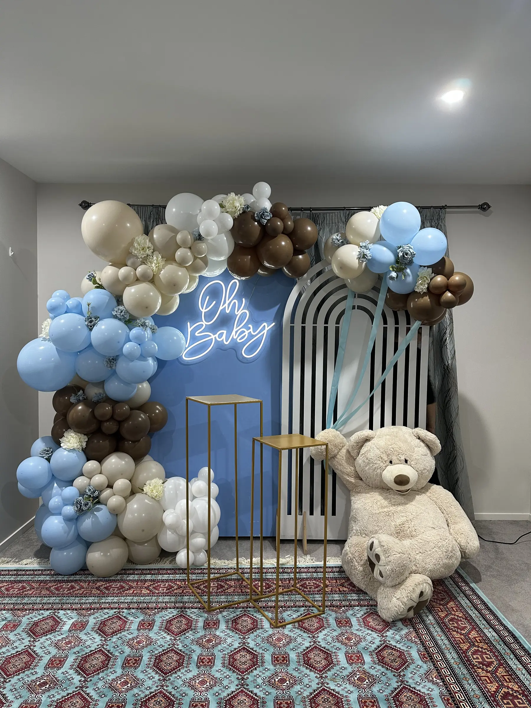 Baby shower styling by Decoration X: 'Oh Baby' blue/brown balloons, teddy bear, white arch board.