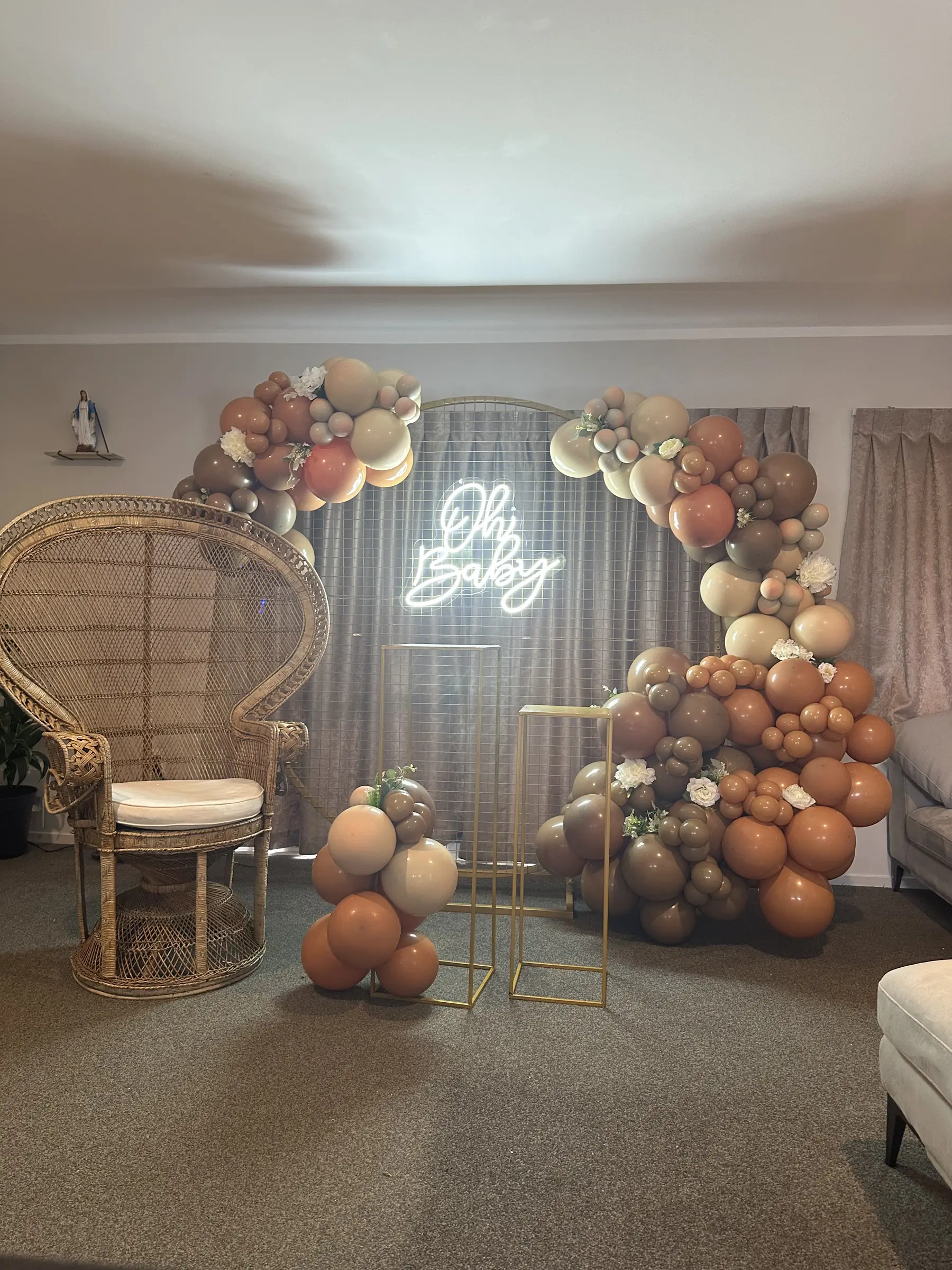 Baby shower styling by Decoration X: 'Oh Baby' neon on gold mesh hoop, peacock chair; living room.