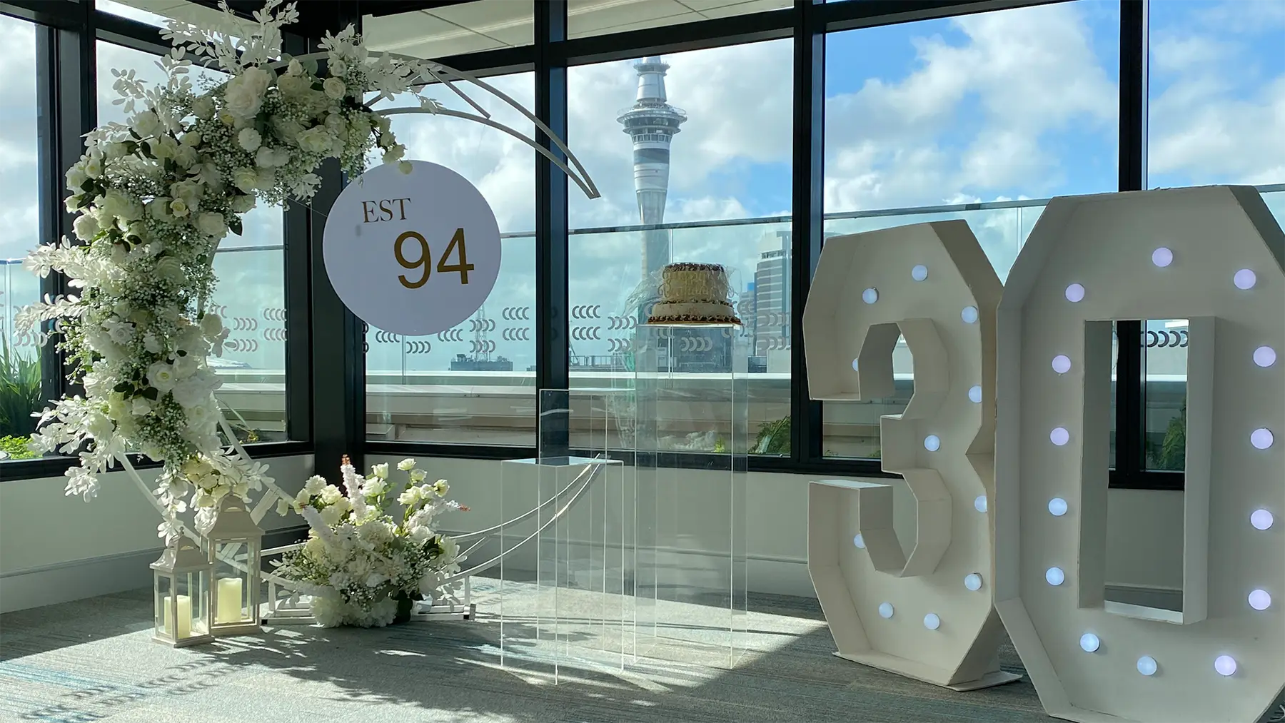Birthday styling by Decoration X: '30' marquee numbers, 'EST 94' sign, Sky Tower view.