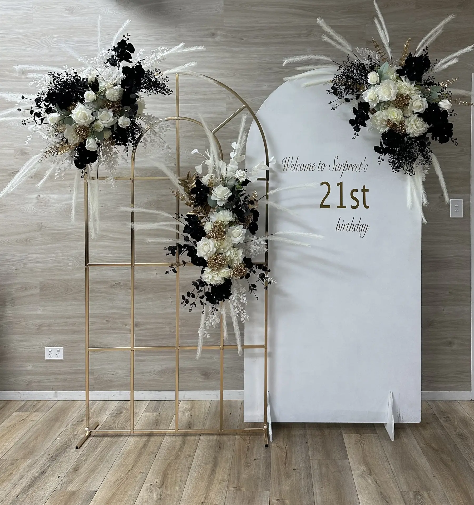 Birthday styling by Decoration X: 'Welcome to Sarpreet's 21st birthday' arch board, black orchids, pampas, gold frame.