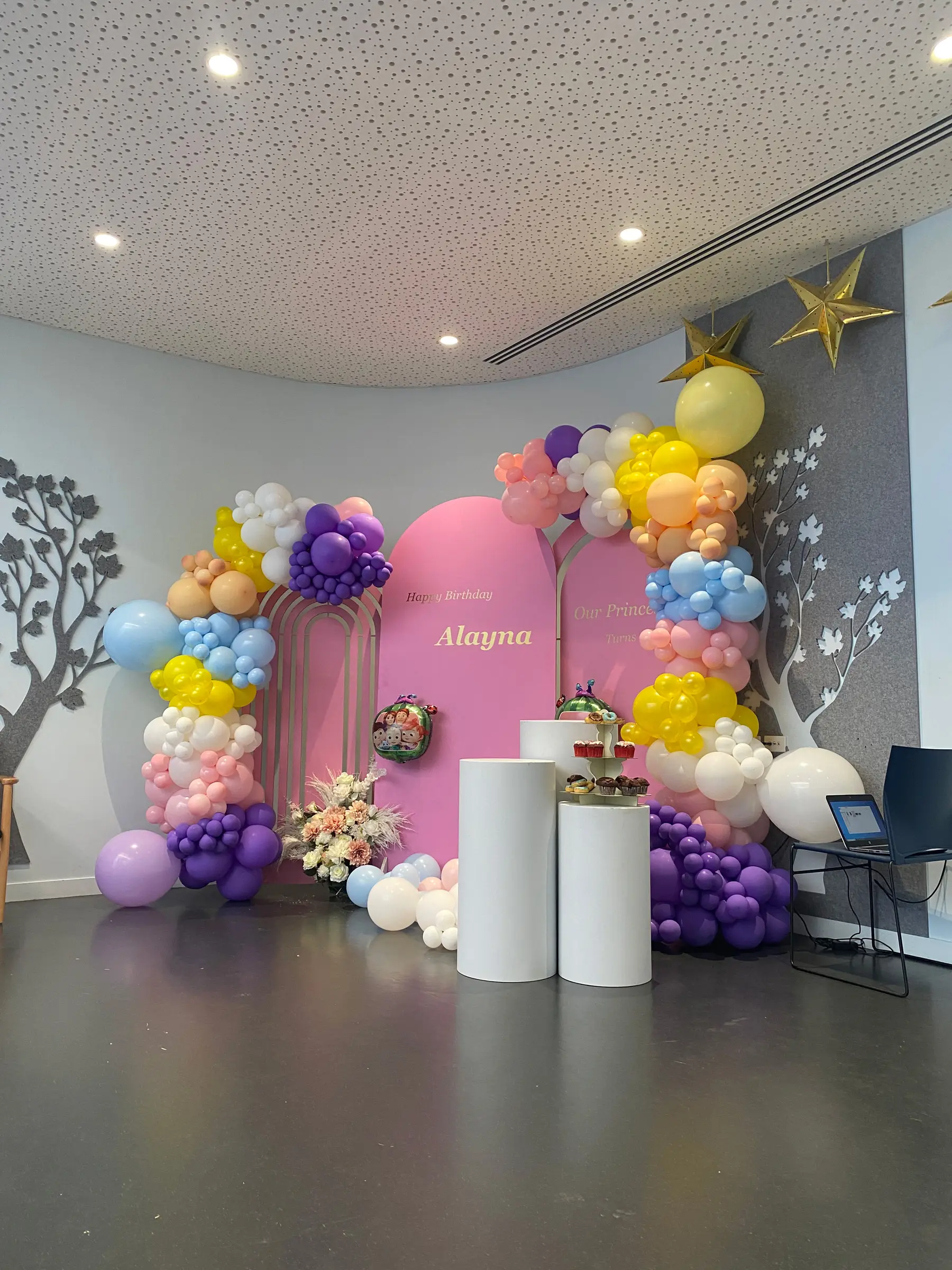 Birthday styling by Decoration X: Rainbow balloon arch, pink name board with tree motif.