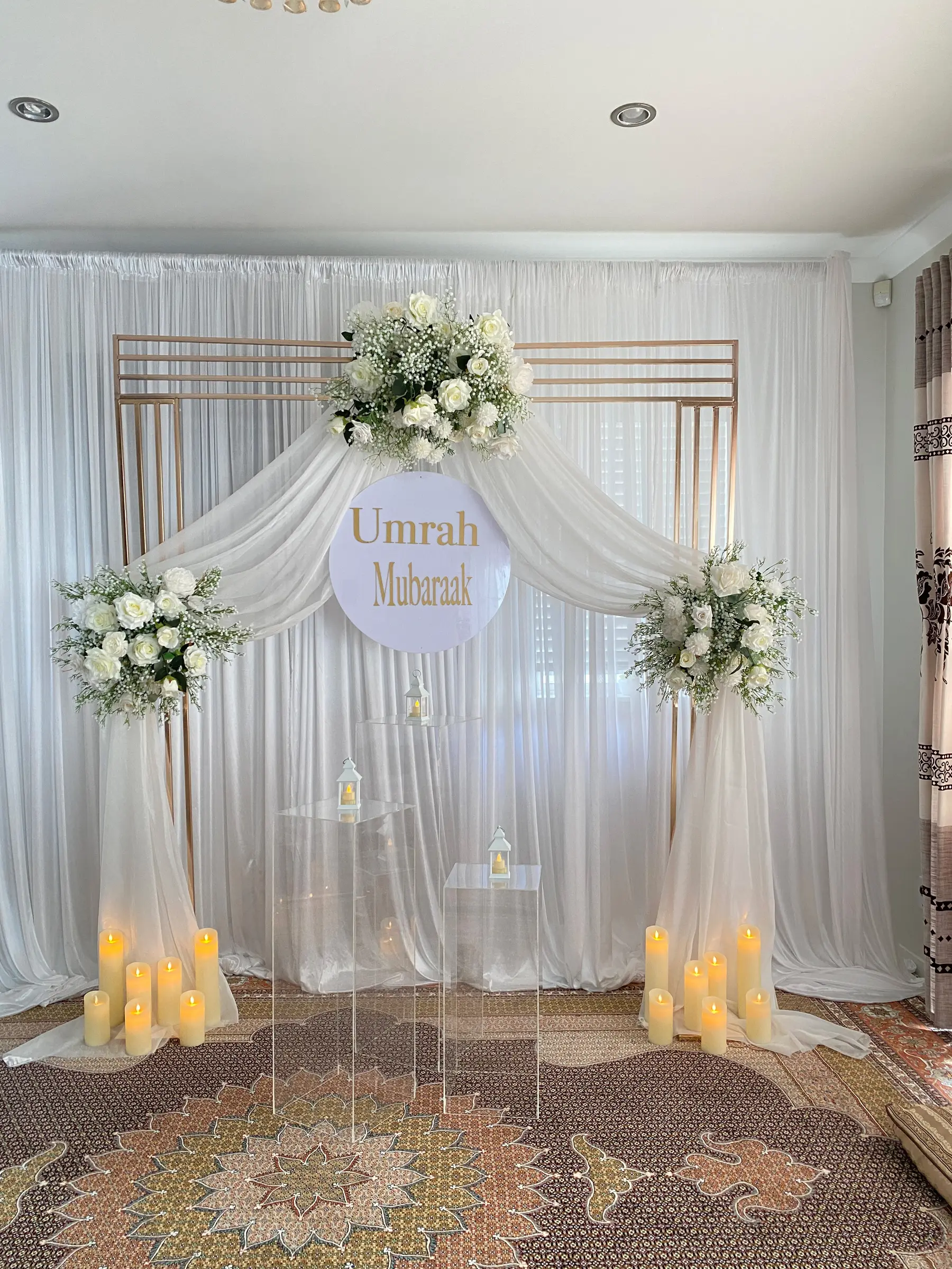 Cultural styling by Decoration X: 'Umrah Mubaraak' round sign, gold frame, drapes, lanterns, candles.