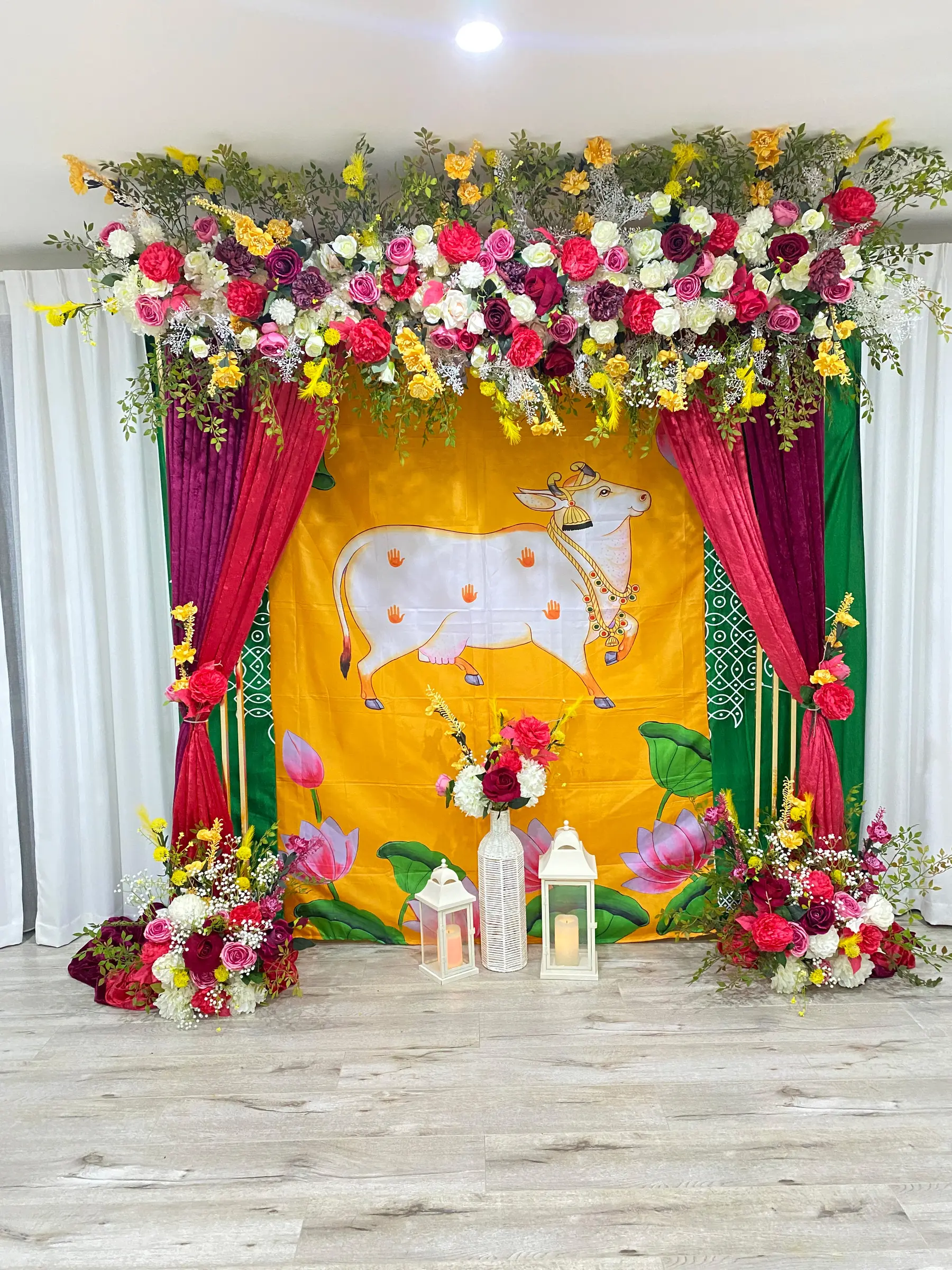 Cultural styling by Decoration X: Pichwai-style painted backdrop, pink roses, drapes, lanterns.