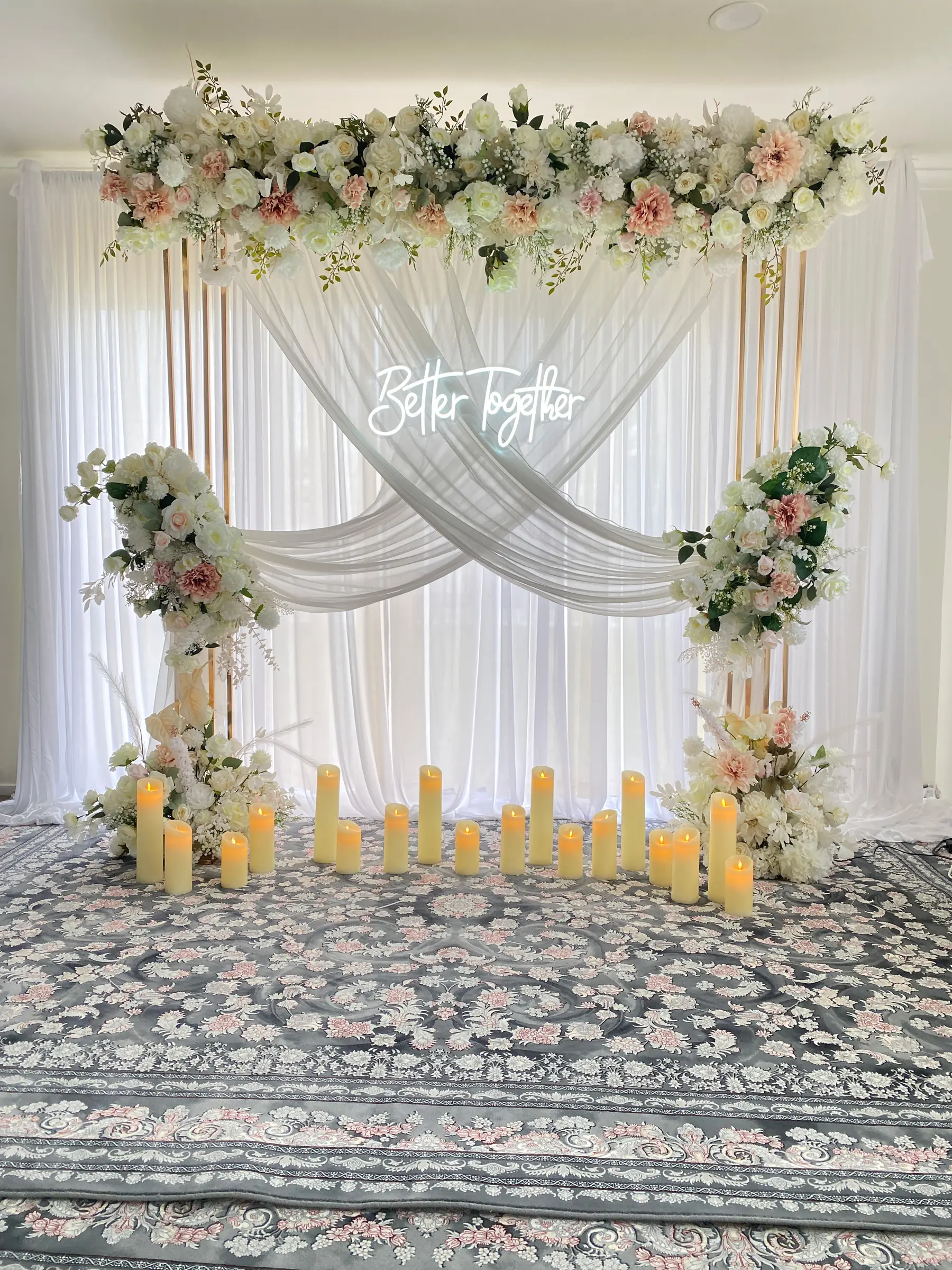 Signage styling by Decoration X: 'Better Together' neon on crossed drapes, blush florals, pillar candles, patterned rug.