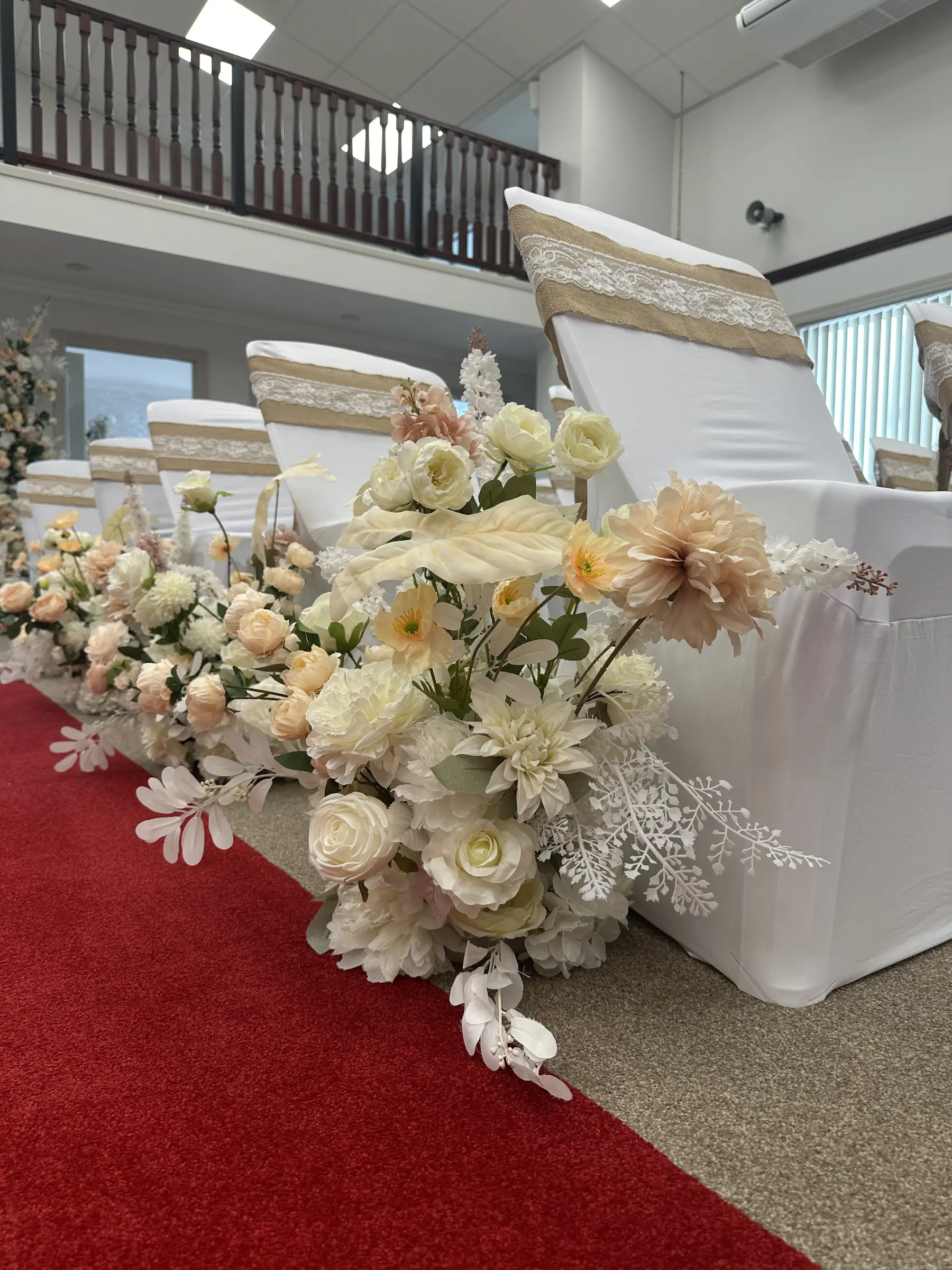 Ceremony styling by Decoration X: White floral pillars on stage steps, red carpet.