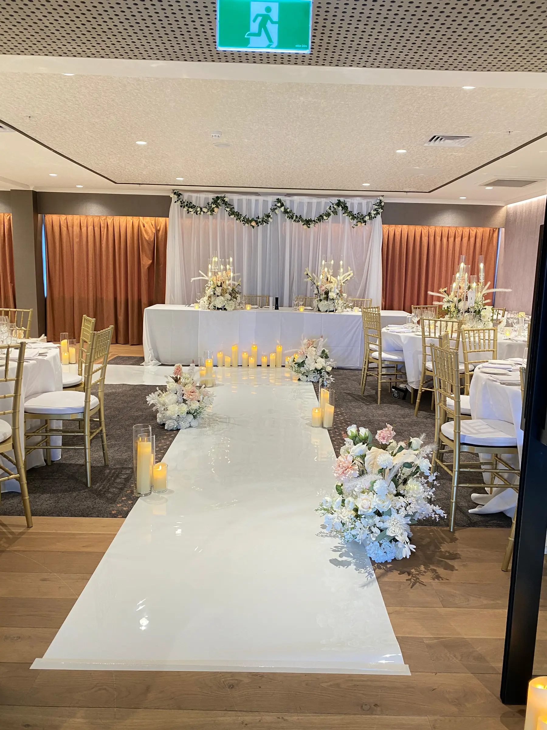 Reception styling by Decoration X: Hall with white drapes, aisle, greenery garland.
