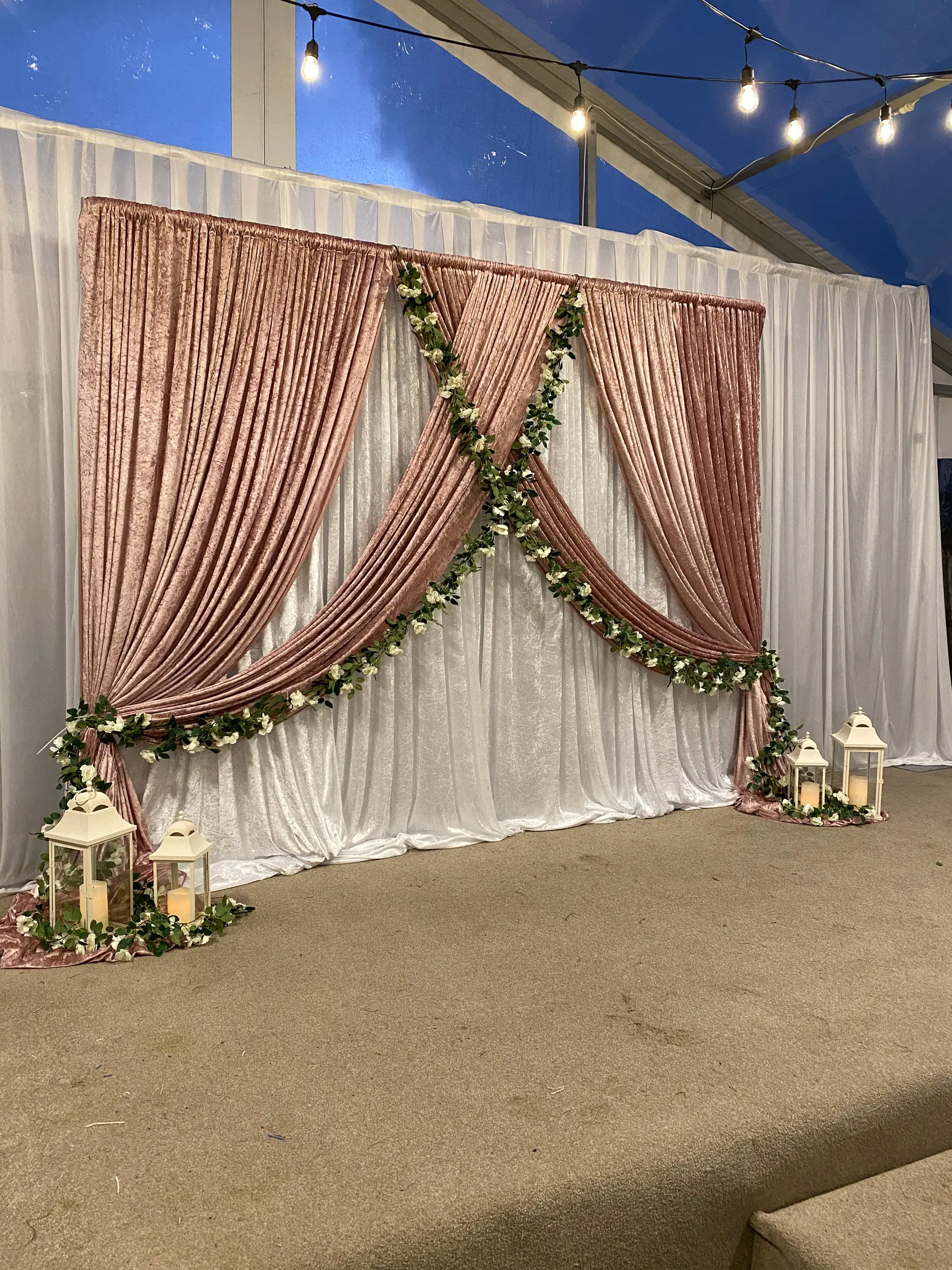 Reception styling by Decoration X: Crushed-velvet rose drapes crossed over white, garland, lanterns; marquee.
